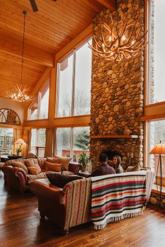 a living room with couches and a stone fireplace at Ambleside Lodge Bed & Breakfast in Canmore