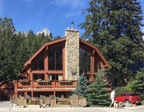 a man walking a dog in front of a log cabin at Ambleside Lodge Bed & Breakfast in Canmore