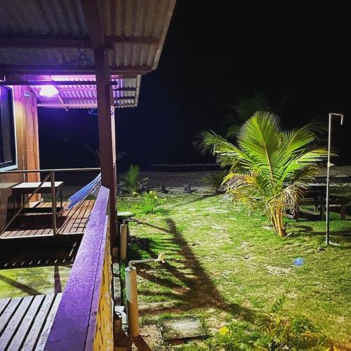 a porch of a house with a palm tree at night at juara seaview chalet, kampung juara in Kampong Juara