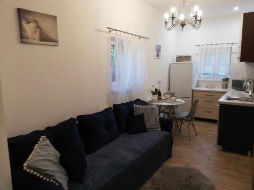 Leśny Apartament II في شتشتنو: غرفة معيشة مع أريكة زرقاء ومطبخ