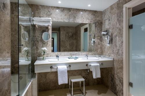 a bathroom with two sinks and a shower and a mirror at Parador de Gijón in Gijón