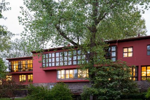 a red building with windows and a tree at Parador de Gijón in Gijón