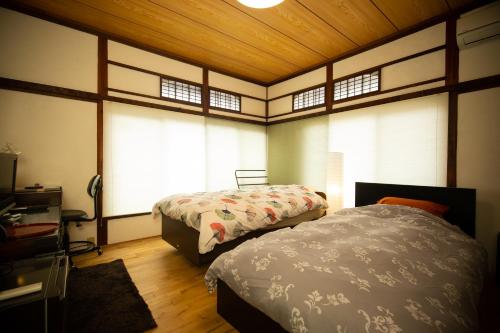 a bedroom with two beds in a room with windows at Kitazawa Cozy House in Tokyo