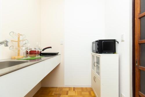 a white kitchen with a sink and a microwave at Kitazawa Cozy House in Tokyo