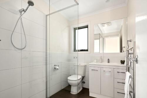 a white bathroom with a toilet and a shower at GRANITE BEACH HOUSE @ Bay of Fires in Binalong Bay