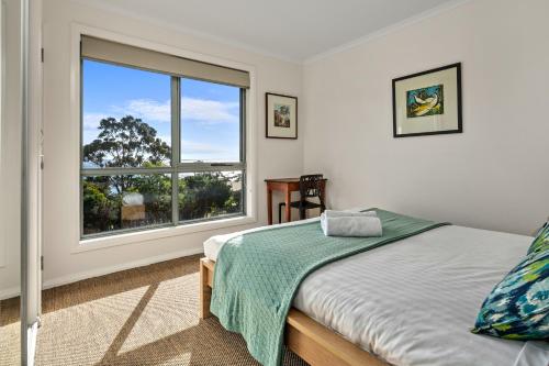 a bedroom with a bed and a large window at GRANITE BEACH HOUSE @ Bay of Fires in Binalong Bay