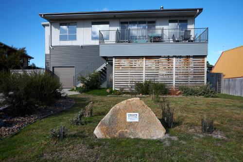 a house with a large rock in front of it at GRANITE BEACH HOUSE @ Bay of Fires in Binalong Bay