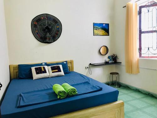 a bedroom with a blue bed with a clock on the wall at Zoni House-Yen Bai in Xóm Soi (2)