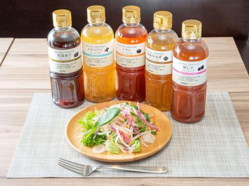 a plate of food with a salad and sauce and bottles of sauce at Super Hotel Sendai Airport Inter in Natori