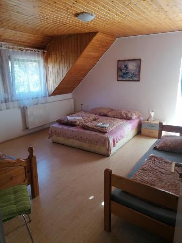 a bedroom with two beds and a wooden ceiling at Kéktúrás-Tóra Nyíló Badacsonyi privát bérlemény in Badacsonytomaj