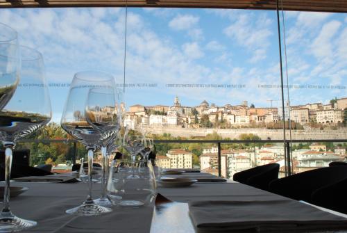 einen Tisch mit Weingläsern auf einem Tisch mit Aussicht in der Unterkunft Hotel Excelsior San Marco in Bergamo