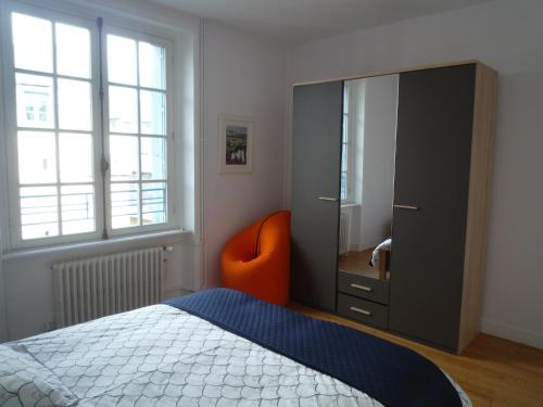 une chambre avec une chaise orange et une commode dans l'établissement Appartement Hypercentre Quimper, à Quimper