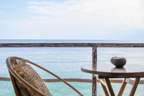 une table et des chaises avec une table et l'océan dans l'établissement Le Cliff Bali, à Uluwatu