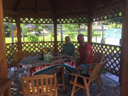 two men sitting at a table in a gazebo at Adenisi guesthouse in Tropojë
