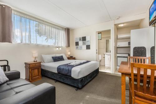 a bedroom with a bed and a table and a couch at Bendigo McIvor Motor Inn in Bendigo