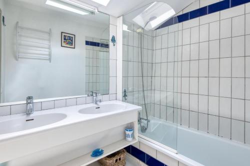 Un baño con dos lavabos, una bañera y un espejo. en Appartement Fauvette, en Saint-Martin-de-Ré