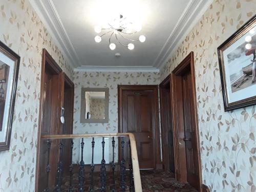 a room with a staircase with a chandelier at Kintrae B&B in Buckie