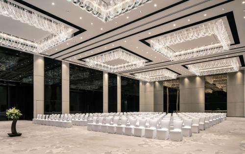 a banquet hall with white chairs and chandeliers at Niccolo Changsha in Changsha