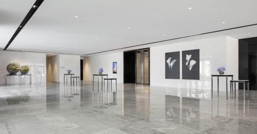 a lobby with a row of tables and paintings on the wall at Niccolo Changsha in Changsha