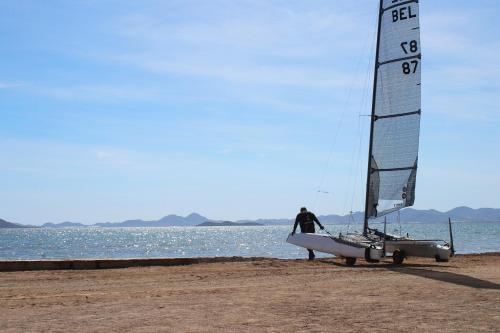 a man standing on a beach with a sail boat at Bungalows Mar Menor, paz a orillas del mar in San Javier