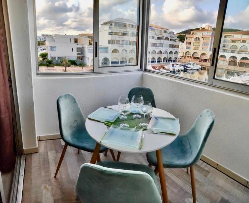 a table and chairs in a room with windows at La Perle Marine, joli appartement avec 1 chambre, Cosy et rénové à 200 m de la plage, vue Marina des Quilles, parking et Wifi in Sète