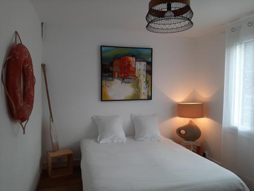 Un dormitorio con una cama blanca y un cuadro en la pared. en La maison des bateaux, en Saint-Valery-sur-Somme