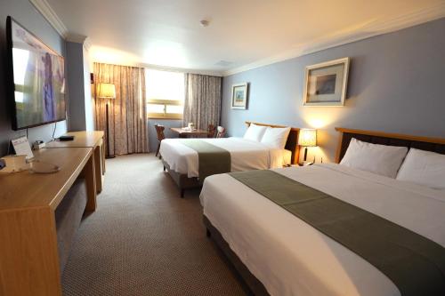 um quarto de hotel com duas camas e uma televisão em Prime Tourist Hotel em Busan