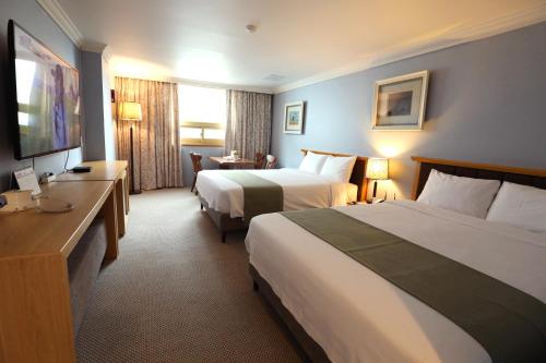 a hotel room with two beds and a television at Prime Tourist Hotel in Busan