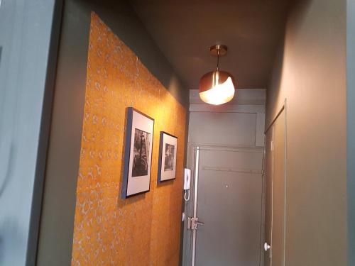 un couloir avec un mur orange et une lumière dans l'établissement le velours des gantiers, confort et hospitalité en plein centre historique, à Rouen