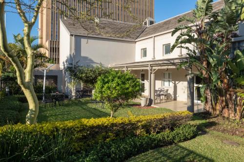 a white house with a garden and trees at City Lodge Hotel Durban in Durban