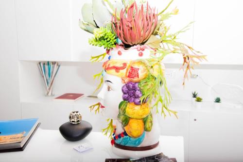 a vase filled with flowers and fruit on a desk at Residenza del Castillo in Palermo
