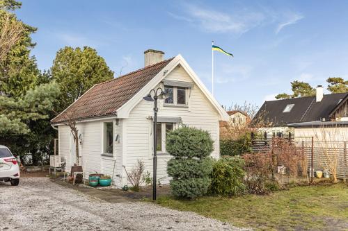 a white house with a car parked in front of it at Guesthouse close to the beaches in Höllviken in Höllviken