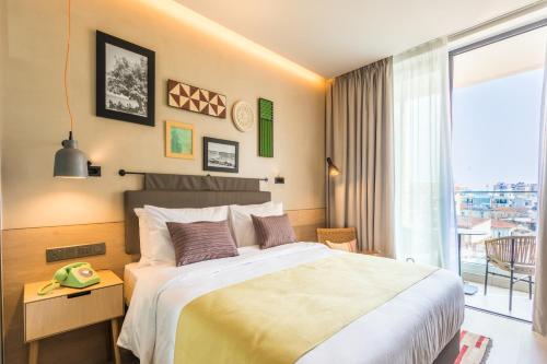 a bedroom with a large bed and a balcony at Hotel Indigo Larnaca - Adults Only, an IHG Hotel in Larnaca