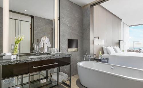 a bathroom with a tub and a bed and a sink at Niccolo Changsha in Changsha