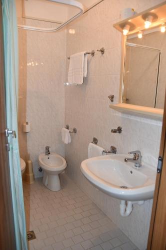 a bathroom with a sink and a toilet and a mirror at Hotel Playa in Bibione