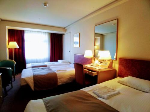 Habitación de hotel con 2 camas y espejo en Tokyo Grand Hotel, en Tokio