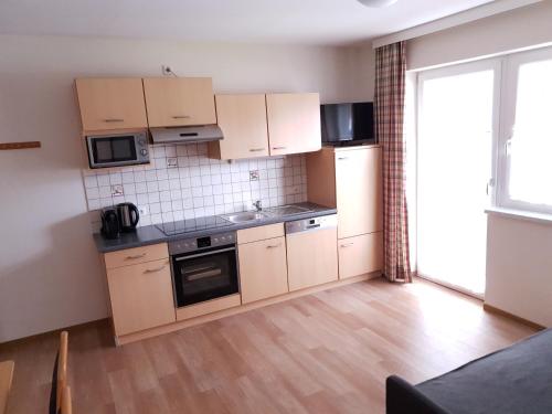 a small kitchen with wooden cabinets and appliances at Aparthotel Pichler in Flachau