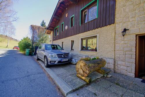 a car parked next to a building with a large rock at Apartmány Tereza in Albrechtice v Jizerských horách