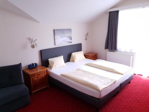 a bedroom with a large bed and a chair at Aparthotel Pichler in Flachau
