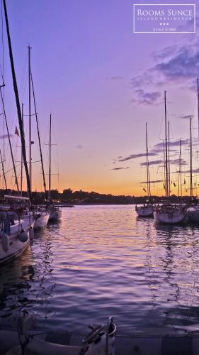 a group of boats sitting in the water at sunset at ꕥ ROOMS SUNCE, Family choice, Best Panoramic view, Supetar Island Brac in Supetar