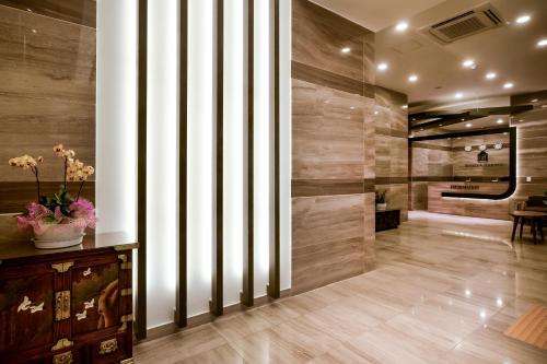 un vestíbulo con paredes de madera y un jarrón de flores en Namyangju Benikea JD Hotel en Namyangju