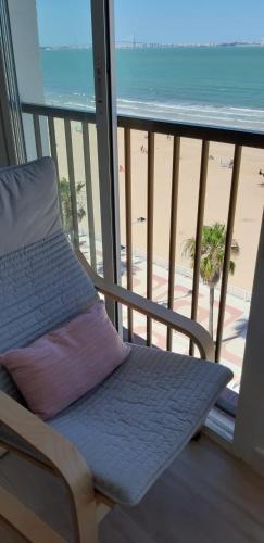 a chair on a balcony with a view of the beach at PRIMERA LINEA DE PLAYA EN VALDELAGRANA in El Puerto de Santa María