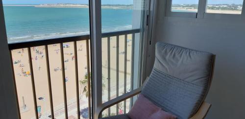 a chair in a balcony with a view of the beach at PRIMERA LINEA DE PLAYA EN VALDELAGRANA in El Puerto de Santa María