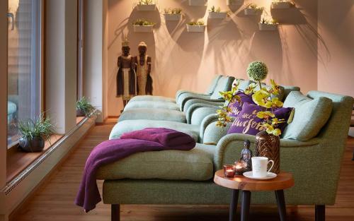 a living room with a green couch and a table at Ayurveda Resort MANDIRA in Bad Waltersdorf
