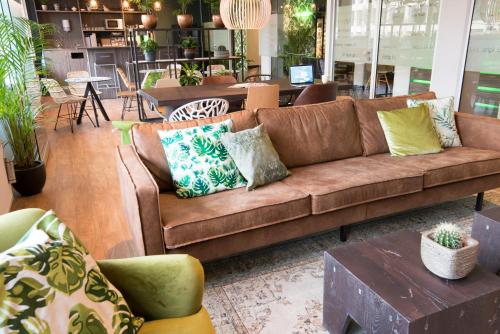 a living room with a brown couch and tables at Court Garden Hotel in The Hague