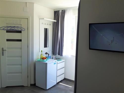 a room with a television and a white refrigerator at Apartmani Dalmacjia in Grebaštica