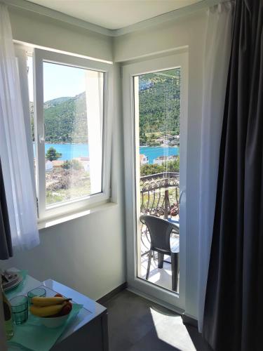 a room with two windows with a view of the ocean at Apartmani Dalmacjia in Grebaštica