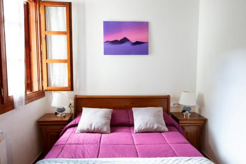a bedroom with a purple bed with two windows at Casa Rural Areano in Escoriaza