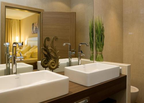 a bathroom with two sinks and a large mirror at Ortner's Resort in Bad Füssing