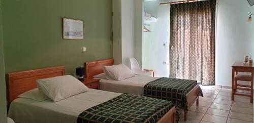 a hotel room with two beds and a window at Zannikos Rooms in Ermoupoli